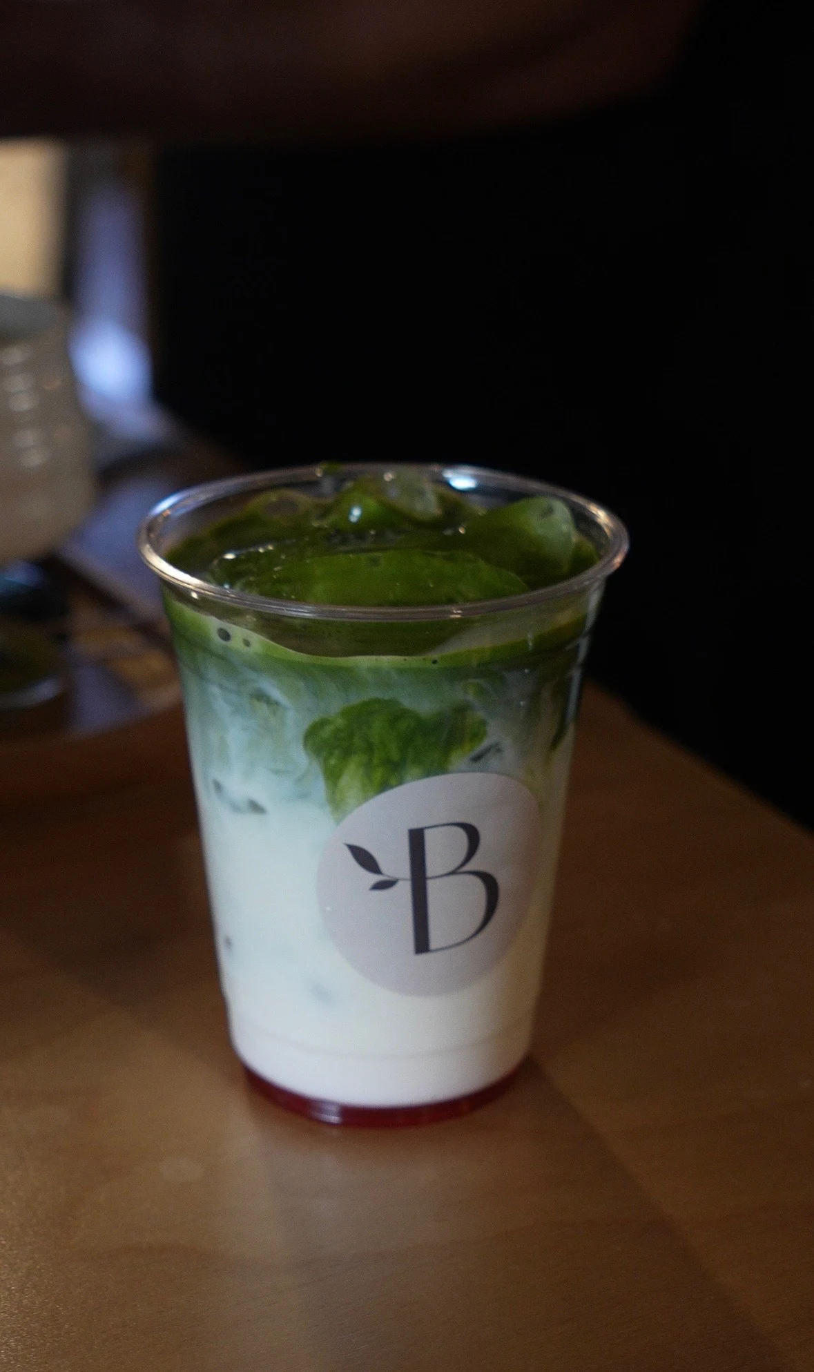 Iced matcha with milk in a clear Bloom Coffee cup